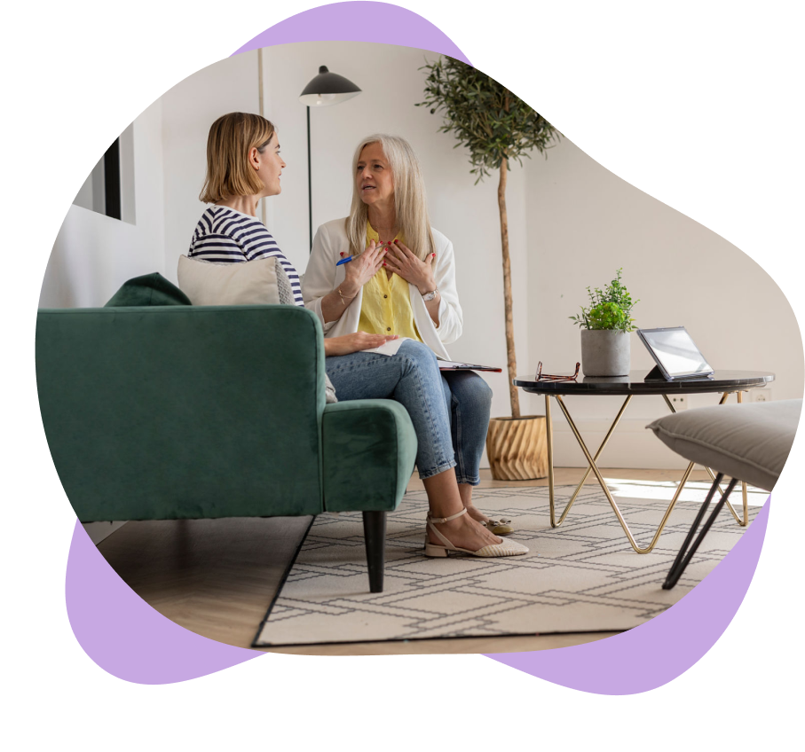 Two women talking on a green couch.