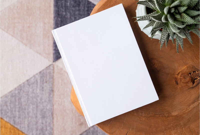 White book on wooden table with plant.