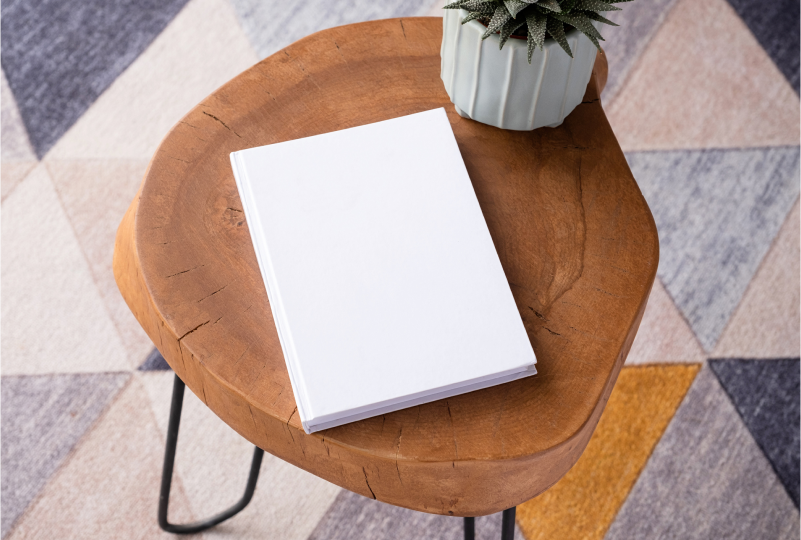Blank book on wooden table with plant.