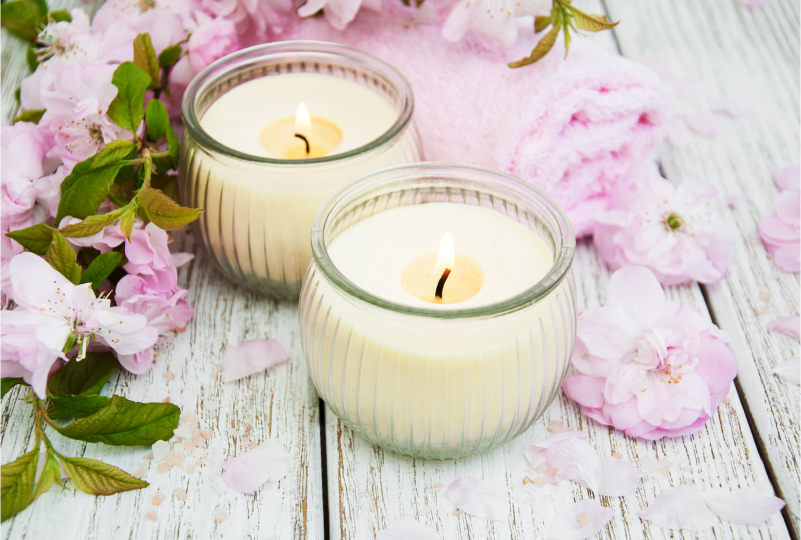 Lit candles and pink flowers on wood.