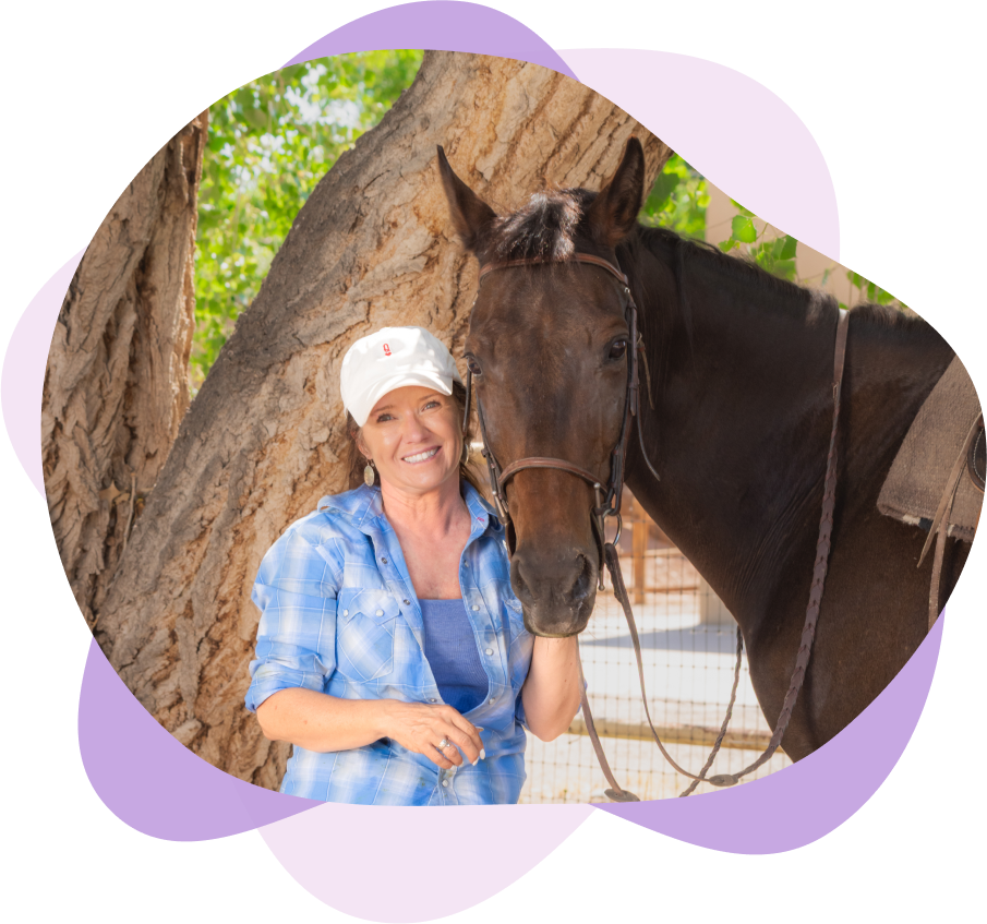 Woman smiling with horse by tree.